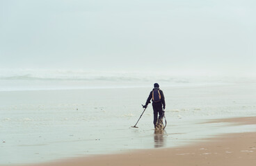 Fototapeta na wymiar Homme utilisant un détecteur de métaux sur une plage