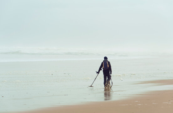Homme utilisant un d&eacute;tecteur  de m&eacute;taux sur une plage