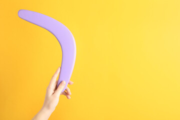 Woman holding boomerang on yellow background, closeup. Space for text