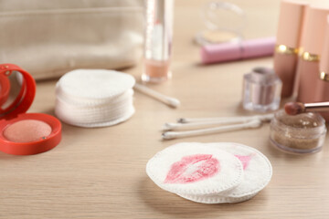 Fototapeta na wymiar Dirty cotton pads, swabs and cosmetic products on wooden table