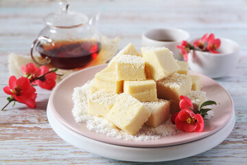 Apple gelatin dessert. Sugar free pastila. Homemade apple marshmallow cubes in coconut flakes and tea, blooming japanese quince decoration