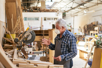 Handwerker Senior mit Mundschutz am Computer