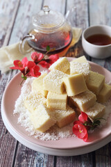 Apple gelatin dessert. Sugar free pastila. Homemade apple marshmallow cubes in coconut flakes and tea, blooming japanese quince decor