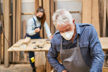 Handwerker Senior mit Mundschutz in Schreinerei