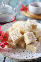 Apple gelatin dessert. Sugar free pastila. Homemade apple marshmallow cubes in coconut flakes and tea, blooming japanese quince decoration