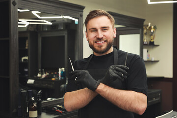 Naklejka na ściany i meble Happy hairdresser with professional tools in barbershop