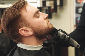 Professional hairdresser working with client in barbershop