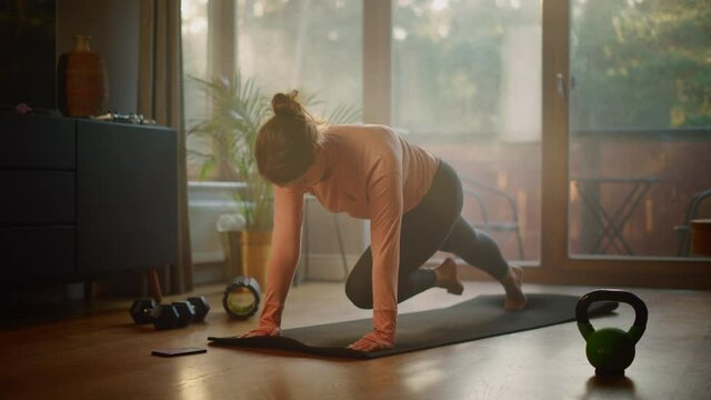 Beautiful Girl Doing Fitness at Home, Using Mobile Smartphone as Timer. Authentic Plus Size Woman Doing Workout, Mountain Climber Steps, Yoga Exercises. Healthy Fit Confident Female. Slow Motion