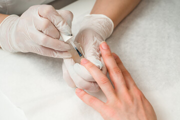 Woman in a nail salon receiving a manicure by a beautician with nail file. Beauty and hand care close-up.