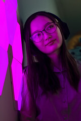 Fototapeta na wymiar Smiling woman with headphones in lilac purple neon light listen to music, nightclub futuristic neon of electronic sound