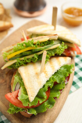 Delicious sandwiches with vegetables and cheese on white table, closeup