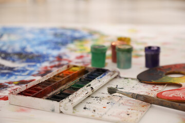 Box of paints and brush on abstract picture