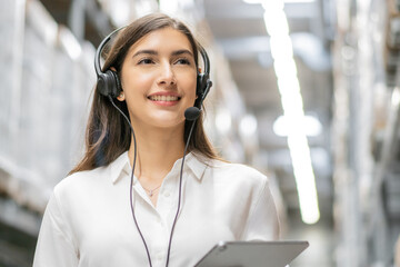 Portrait of smiling warehouse woman staff listening and talking to customer with headset working in distribution factory. female call center or support operator working for online shopping.