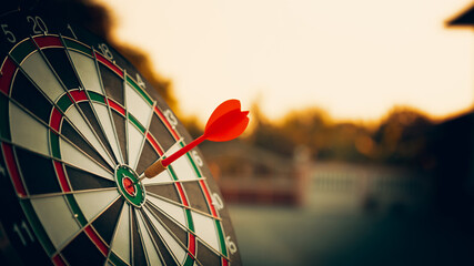 bullseye target or dart board has red dart arrow throw hitting the center of a shooting for...