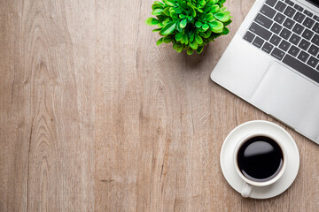 Flat lay, top view office table desk. Workspace with, laptop,office supplies, pencil, green leaf, and coffee cup on wood background.