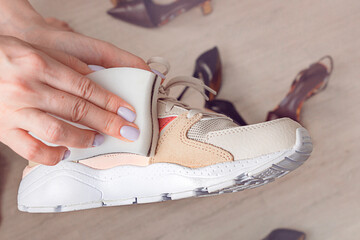 Cleaning sport shoes. Female hands holding  melamine spong and sport sneakers