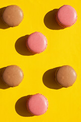 Chocolate and berry sweet macaron cookies patter on yellow background. Flat lay, top view.