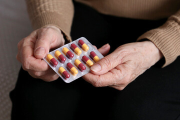 Elderly woman with pills in wrinkled hands. Medication in capsules, taking sedatives, antibiotics or vitamins