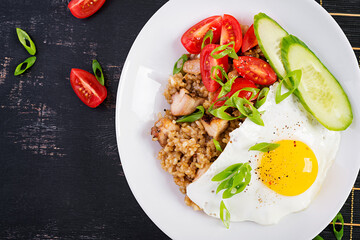 Nasi Goreng. Indonesian chicken fried rice on dark background. Nasi Goreng is an indonesian cuisine dish with rice, chicken meat, onion, egg, vegetables. Top view, above, copy space