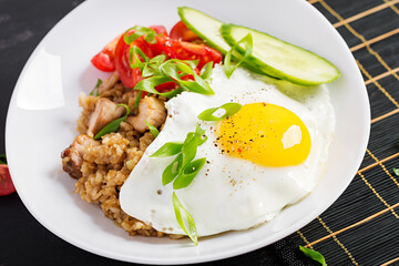 Nasi Goreng. Indonesian chicken fried rice on dark background. Nasi Goreng is an indonesian cuisine dish with rice, chicken meat, onion, egg, vegetables.