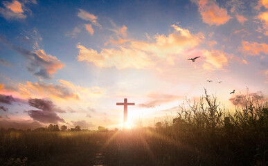 Fototapeta na wymiar black cross religion symbol silhouette in grass over sunset sky background