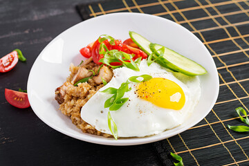 Nasi Goreng. Indonesian chicken fried rice on dark background. Nasi Goreng is an indonesian cuisine dish with rice, chicken meat, onion, egg, vegetables.