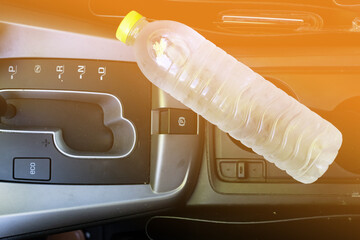 A plastic drinking water bottle in hot car with sunlight effect. Summer danger, The risk comes from the bottle of water being left in a car that's in direct sunlight.