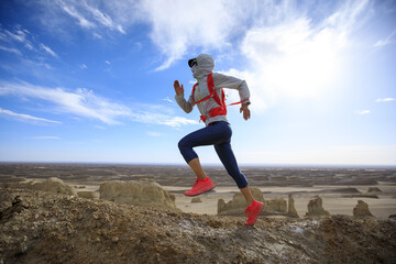 Woman trail runner cross country running  on sand desert dunes