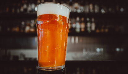 glass of light beer stands on bar counter in a bar or pub