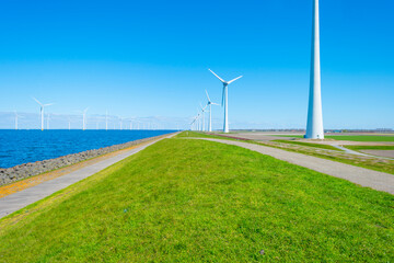 Fototapeta na wymiar Wind turbines for renewable energy in a lake in bright blue sunlight in spring, Noordoostpolder, Flevoland, The Netherlands, April 26, 2021