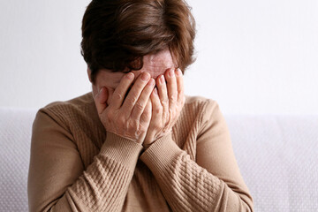 Elderly woman covering her face with hands. Crying person, upset and sadness concept