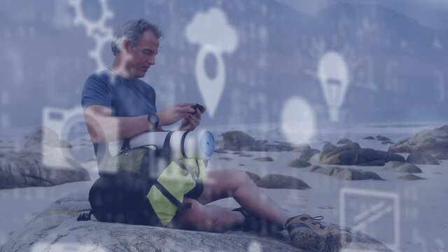 Animation of digital online icons and binary coding over senior man by seaside using smartphone - Powered by Adobe