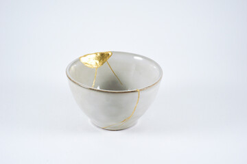 Grey broken pottery restored with Kintsugi, representation of broken heart with pottery.