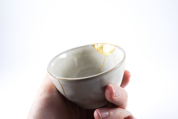 Grey broken pottery restored with Kintsugi, representation of broken heart with pottery.