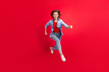 Full length body size photo of cheerful girl jumping up running fast isolated vibrant red color background