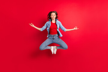 Full length body size photo of cheerful girl jumping up practising yoga asana meditating isolated vibrant red color background