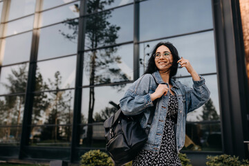 Happy young woman walking on city streets with a leather backpack, smiling. - Powered by Adobe