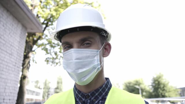 Builder in medical mask and hard hat outdoors