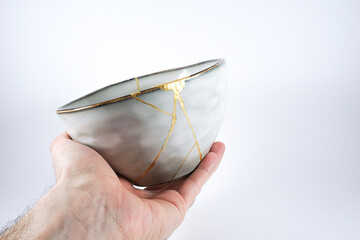 Grey broken pottery restored with Kintsugi, representation of broken heart with pottery.