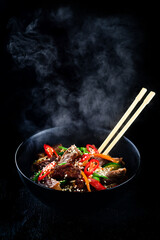 Stir fry soba noodles with beef and vegetables in wok on dark background, Asian noodles with beef...