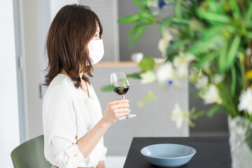 マスクをしてワインを飲む若い女性