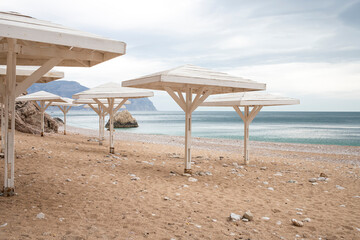 Wooden awnings on a deserted sandy beach overlooking the sea.