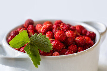 Fresh wild strawberries in small white bowl, close-up