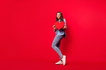 Full length body size view of attractive cheerful girl holding in hands amour heart copy space isolated over vivid red color background