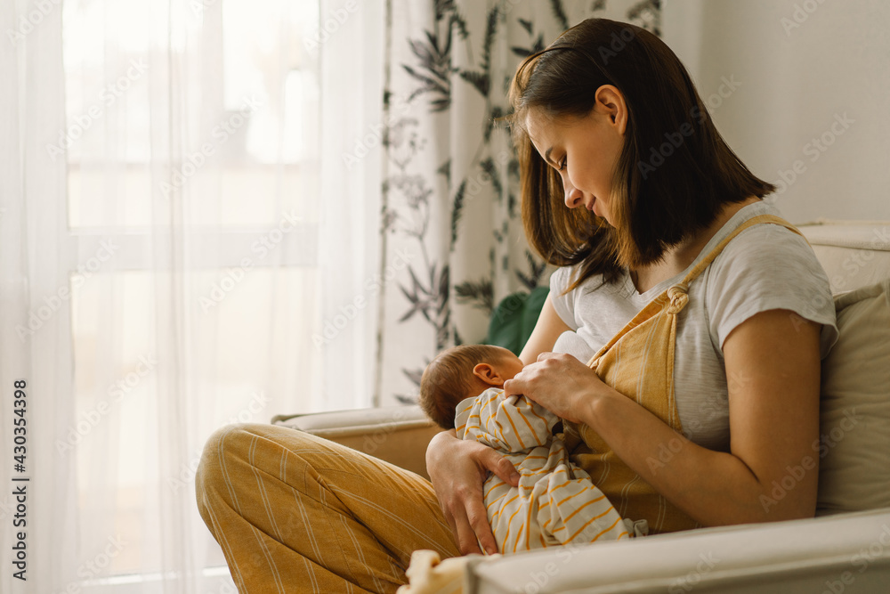 Wall mural newborn baby boy sucking milk from mothers breast. portrait of mom and breastfeeding baby.