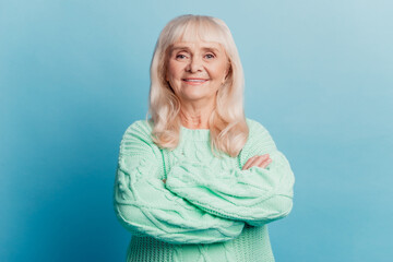 Portrait of cheerful aged mature woman stand with crossed arms over blue background