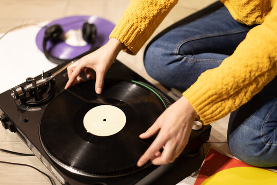 girl hands puts record on turntable. Relaxed lounging at home with vinyl record player sitting on floor. Musical relaxation concept. anti-digital hobby, lockdown pastime