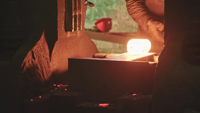 Unrecognizable forger man using hydraulic press for shaping steel in forgery shop