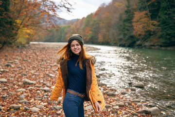 Naklejka na ściany i meble woman in a yellow jacket near the river in nature autumn travel