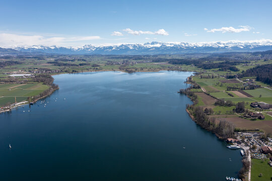 Luftaufnahme vom Greifensee im Vordergrund und den schneebedeckten Bergen der Alpen im Hintergrund, Z&uuml;rich, Schweiz